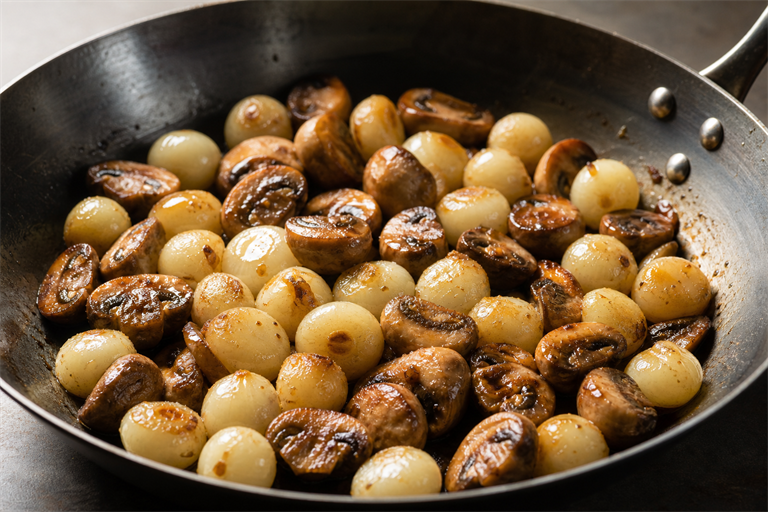 Step 7: glazed pearl onions and golden seared button mushrooms resting in a wide carbon