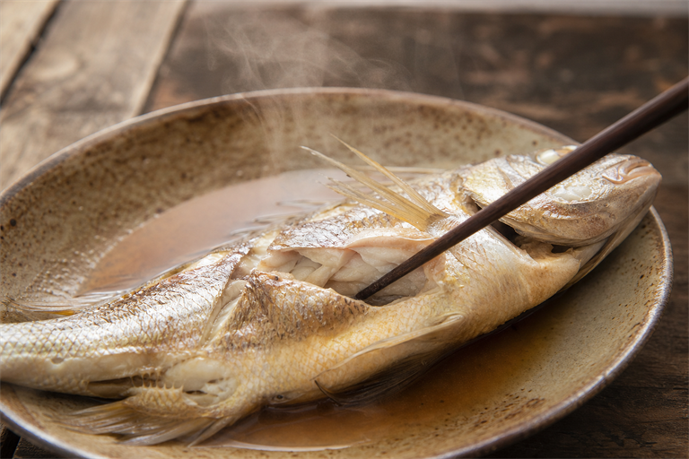 Step 4: a chopstick tip slid into a diagonal slash on a steamed whole fish, flesh just o