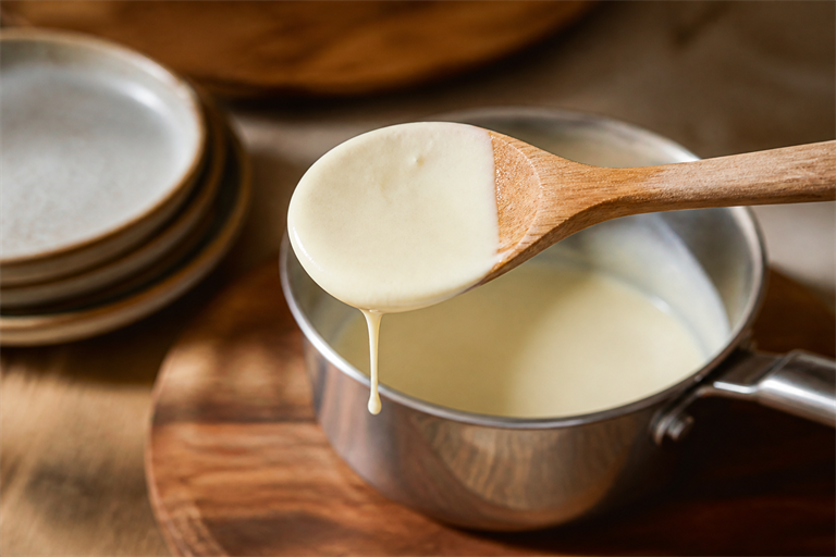 Step 6: finished beurre blanc coating the back of a wooden spoon, pale ivory colour, sat