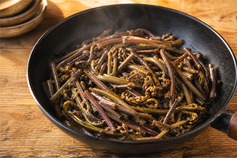 Step 5: rehydrated gosari fernbrake stir-frying in a black skillet with soup soy sauce a