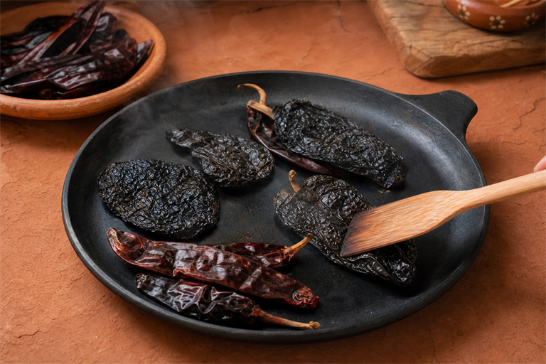 Step 1: flattened dried ancho mulato and pasilla chiles toasting on a black cast iron co