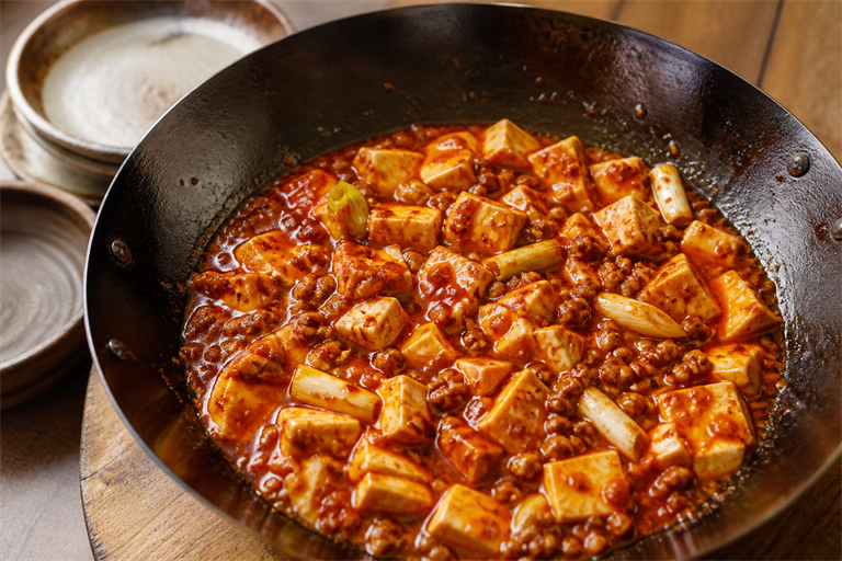 Step 8: glossy red mapo tofu in a wok after slurry thickening, sauce clinging to silken 