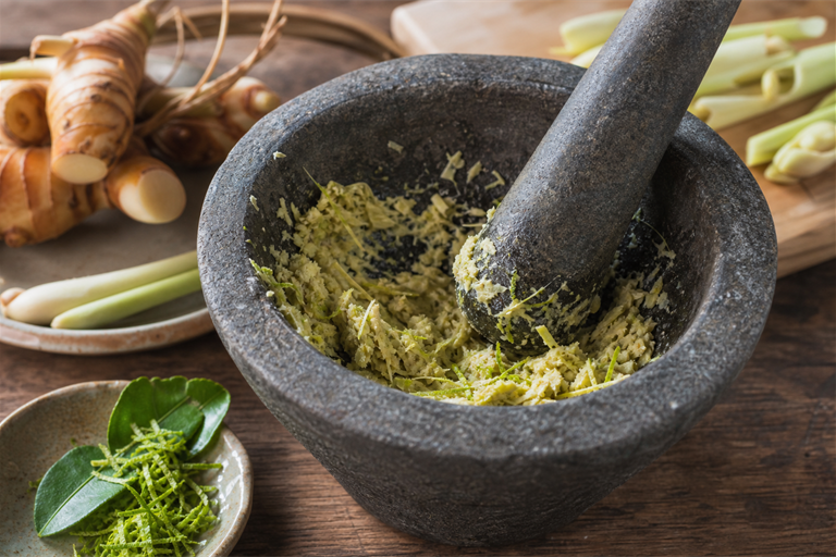 Step 3: bruised lemongrass and kaffir lime zest being pounded together with galangal in