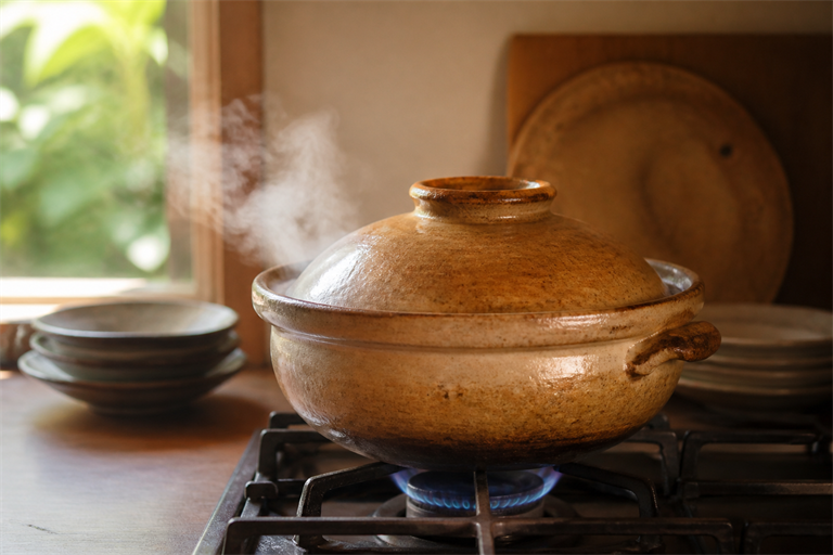 Step 5: a covered donabe on a low gas flame with a wisp of steam escaping the lid seam,