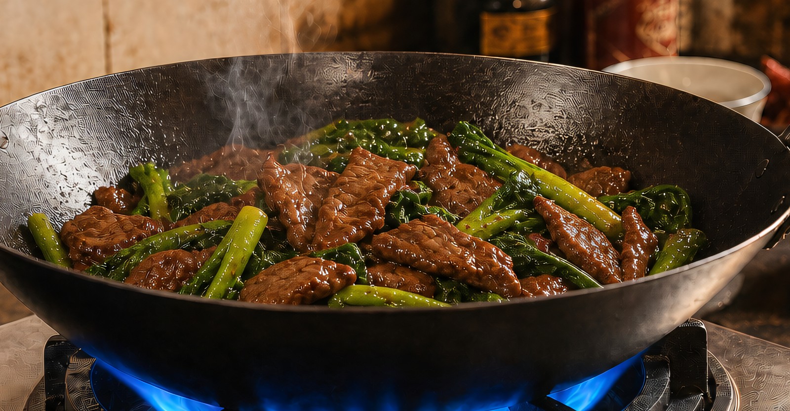 A finished stir-fry of beef and Chinese broccoli with glossy wok-hei sheen in a carbon-steel wok over a blue flame